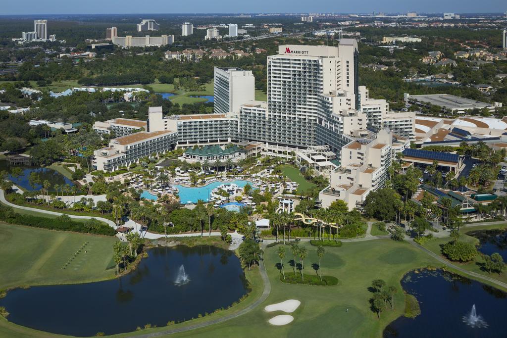 An ariel perspective photograph of a large hotel surrounded by golf courses and trees