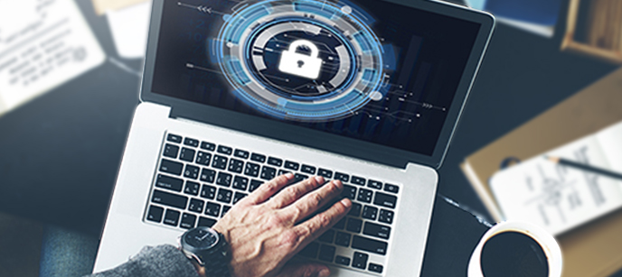 Man with hand over keyboard of an open laptop. The laptop rests on a table with documents that are not in focus. The screen on the laptop displays a padlock..